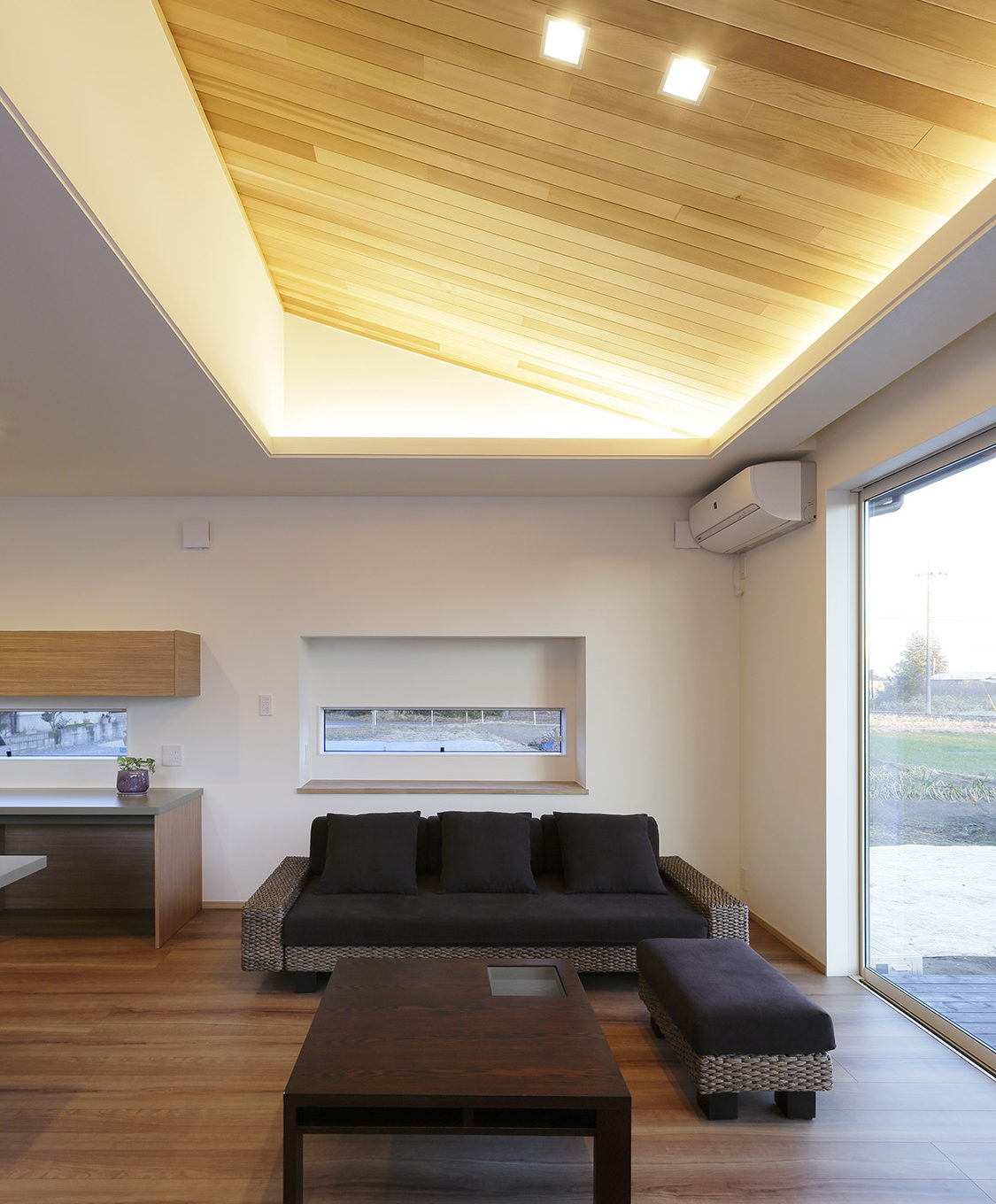 リビング　：　一部勾配天井とし、仕上げをレッドシダーに。間接照明がレッドシダーを照らし木の質感を引き立てる。