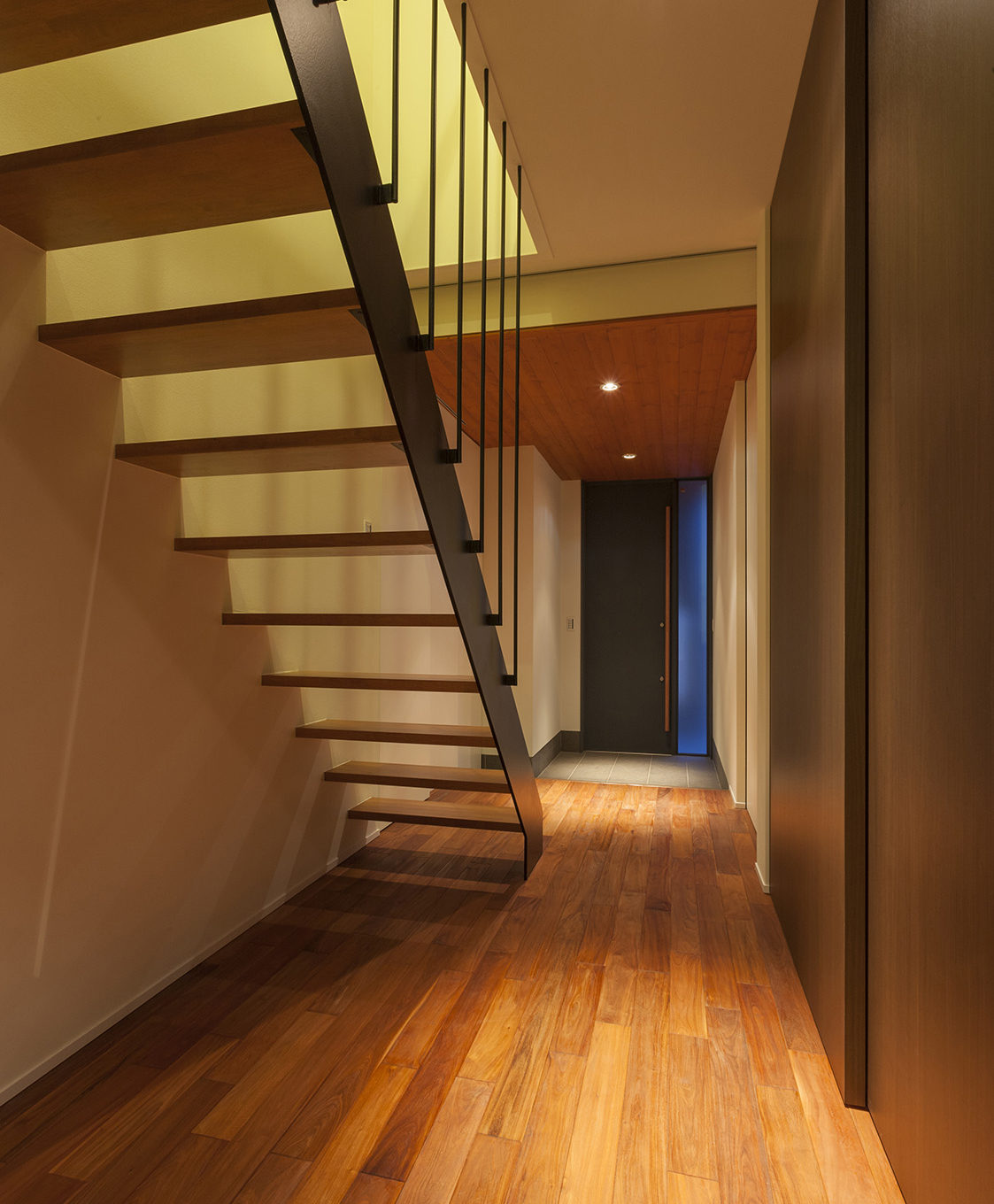 玄関ホール：床材はピンカドの無垢材を使用。鋼製の玄関扉と赤松の天井材が印象的。