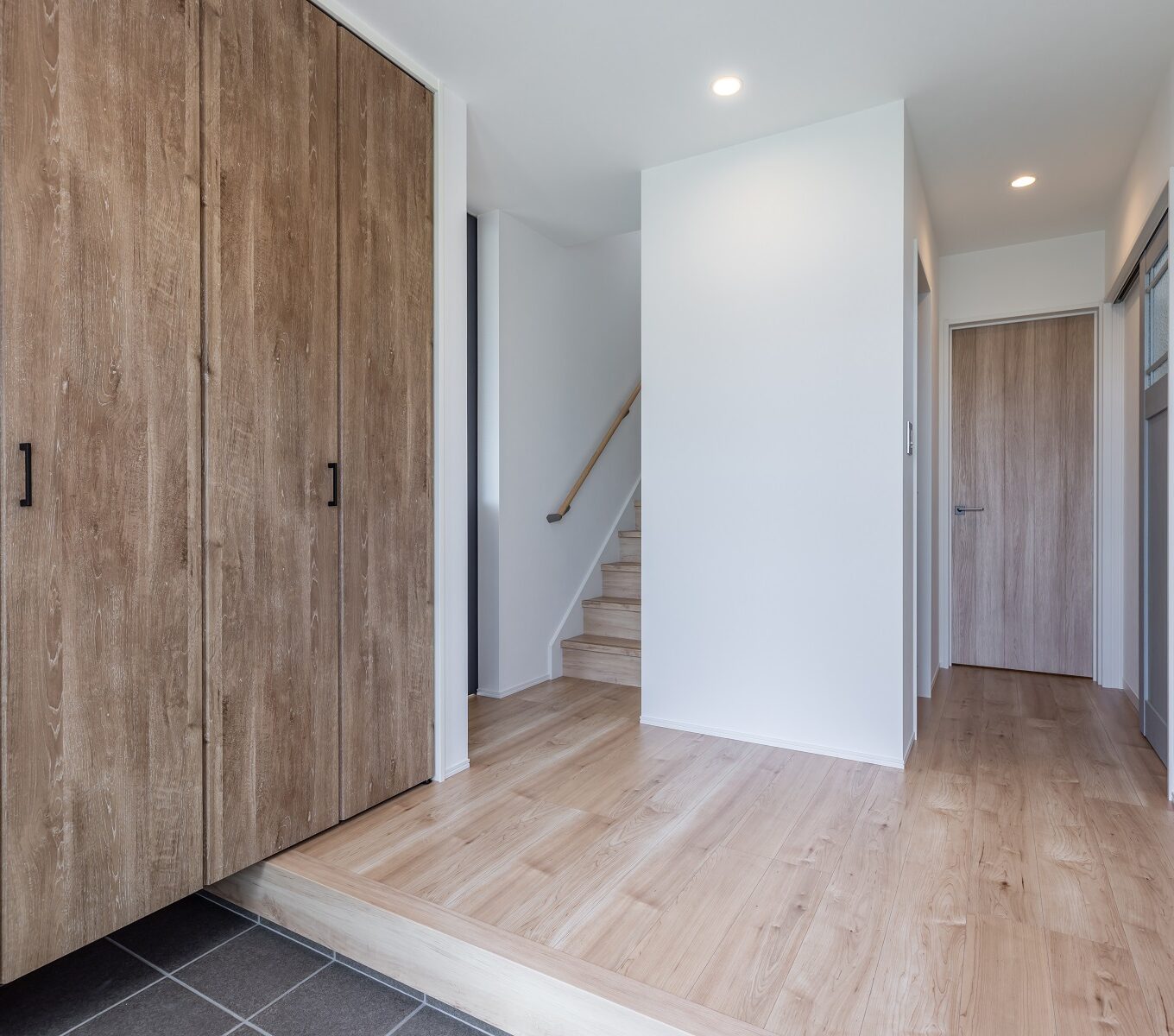 玄関には、家族全員分の靴を収納できる大きな扉付きの靴箱を用意。 備え付けのコート掛けは、雨の日のレインコートや冬の日のコートの定位置に。 シューズインクローゼットとしてつくらなかった分、土間部分を広く使えるようにしました。